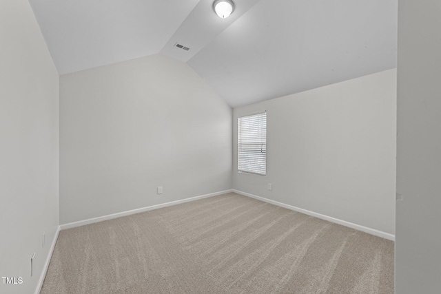 carpeted empty room with vaulted ceiling, visible vents, and baseboards