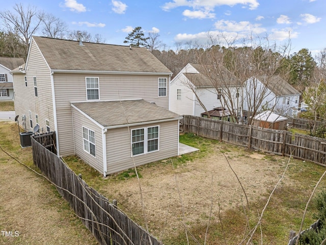 rear view of property featuring a fenced backyard, roof with shingles, and a yard