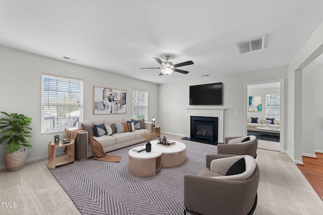 living area with a fireplace with flush hearth, a wealth of natural light, and visible vents