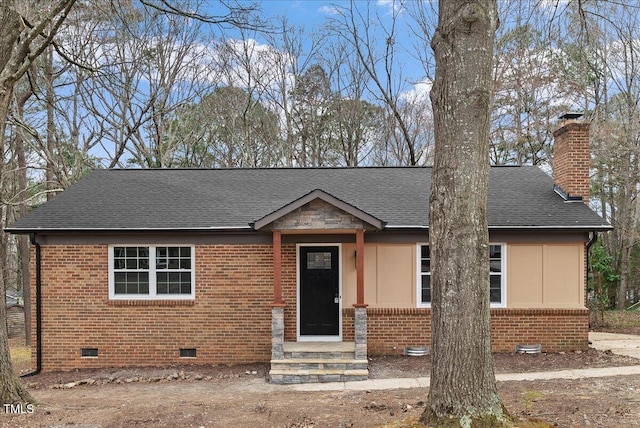 view of front of property with a shingled roof, crawl space, brick siding, and a chimney