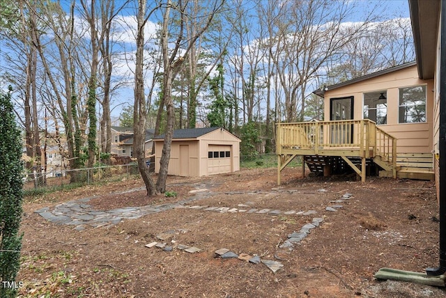 view of yard with a garage, driveway, an outbuilding, fence, and a wooden deck