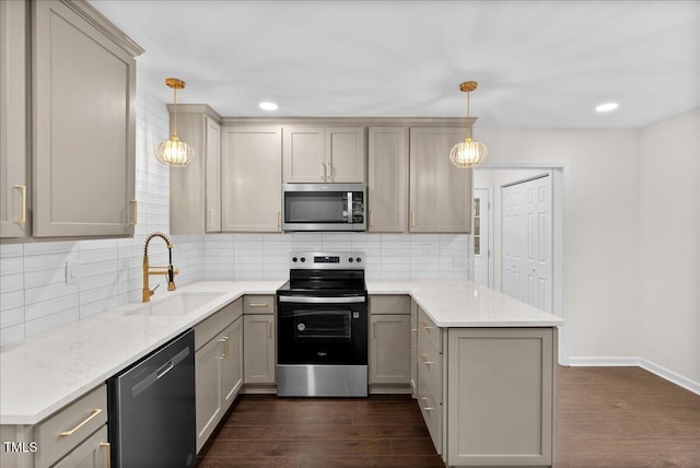 kitchen with stainless steel appliances, a peninsula, a sink, gray cabinets, and dark wood finished floors