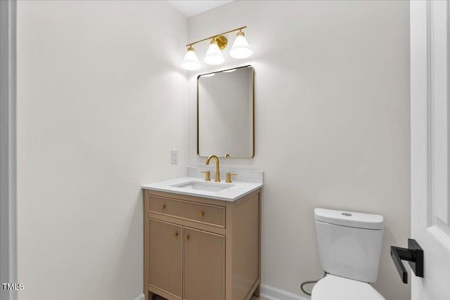 half bathroom with vanity, toilet, and baseboards