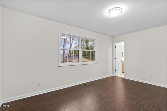 unfurnished room featuring wood finished floors, visible vents, and baseboards