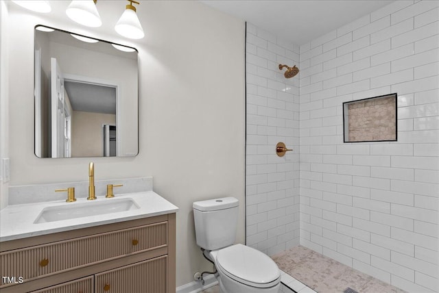 bathroom featuring a tile shower, vanity, and toilet