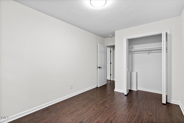 unfurnished bedroom featuring a closet, baseboards, and dark wood-type flooring