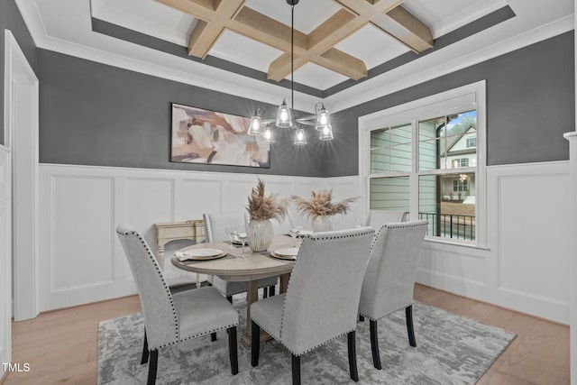 dining room featuring a wainscoted wall, a decorative wall, light wood-type flooring, coffered ceiling, and beamed ceiling