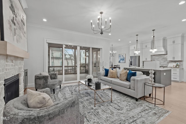 living area featuring a stone fireplace, recessed lighting, light wood-style floors, an inviting chandelier, and crown molding