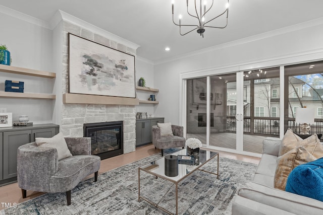 living area with light wood-type flooring, ornamental molding, a fireplace, and a notable chandelier