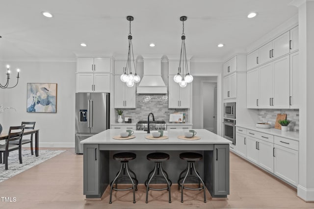 kitchen featuring white cabinets, ornamental molding, appliances with stainless steel finishes, custom exhaust hood, and a kitchen bar