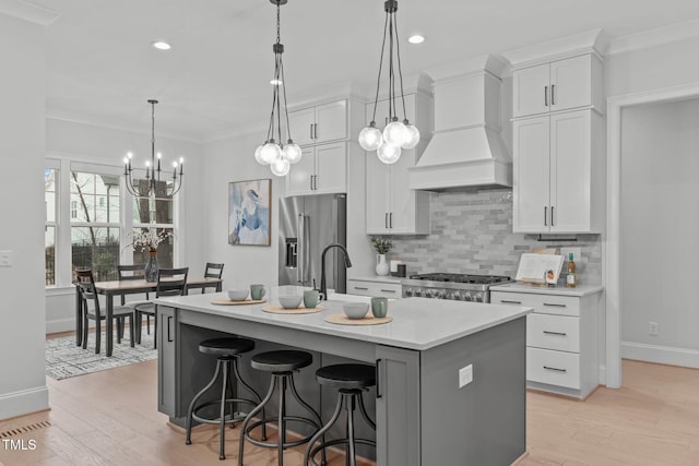 kitchen featuring high quality fridge, light countertops, custom exhaust hood, tasteful backsplash, and crown molding