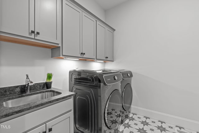 laundry area featuring light floors, cabinet space, a sink, washer and dryer, and baseboards