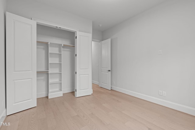 unfurnished bedroom featuring light wood-type flooring, a closet, and baseboards