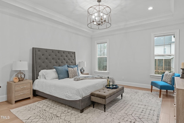 bedroom featuring light wood finished floors, a tray ceiling, an inviting chandelier, and baseboards