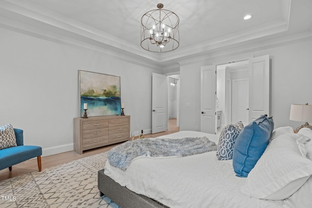 bedroom featuring a chandelier, a raised ceiling, crown molding, and light wood-style flooring