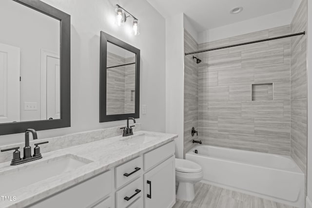 bathroom with toilet, double vanity, shower / washtub combination, and a sink