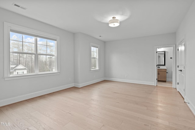 spare room featuring light wood-style floors, visible vents, and baseboards