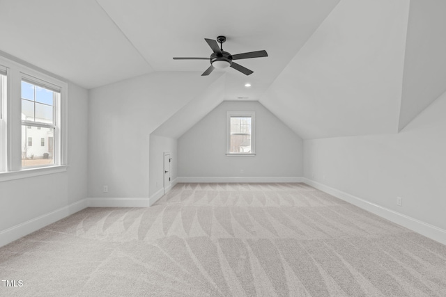 bonus room with light carpet, vaulted ceiling, a ceiling fan, and baseboards