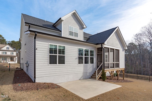 view of front of property with a shingled roof, a sunroom, a patio, and fence