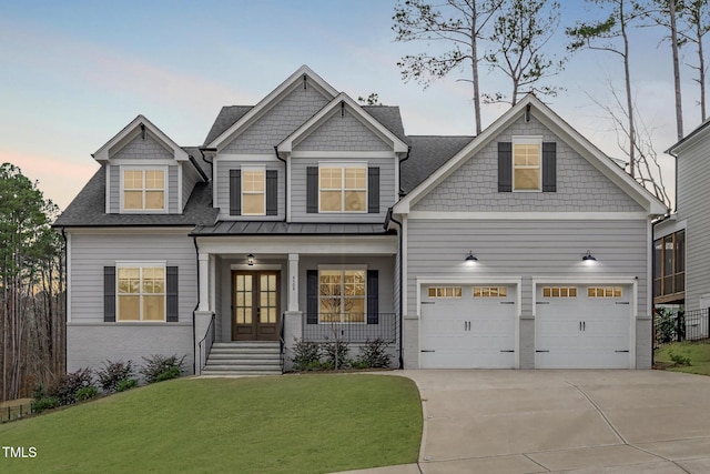 craftsman-style house with driveway, a porch, a front yard, and french doors