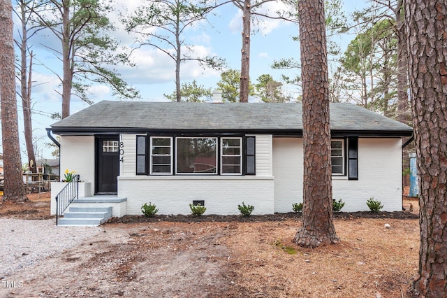 view of front of property featuring crawl space, brick siding, and roof with shingles