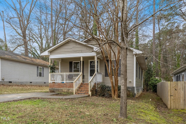 bungalow-style house featuring a porch, crawl space, a front yard, and fence