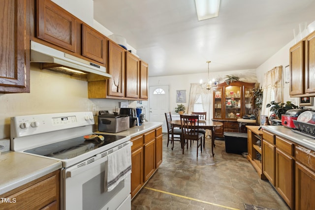 kitchen with electric stove, brown cabinets, light countertops, and under cabinet range hood