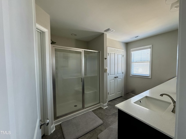 full bath featuring double vanity, a stall shower, visible vents, and a sink