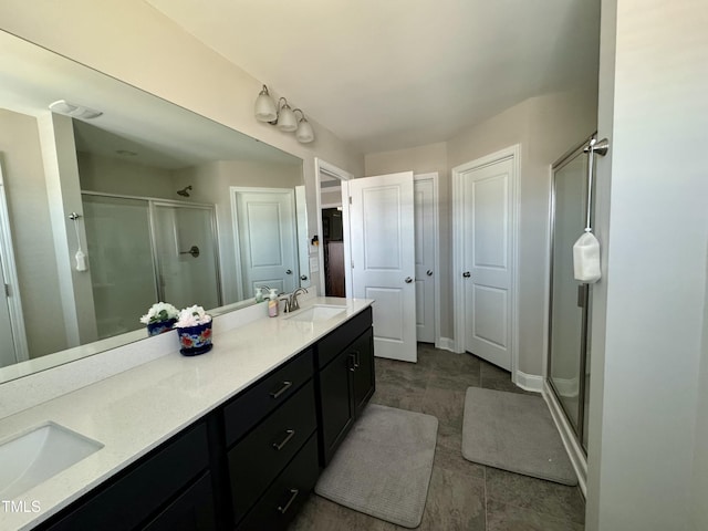 full bathroom with a stall shower, a sink, baseboards, and double vanity