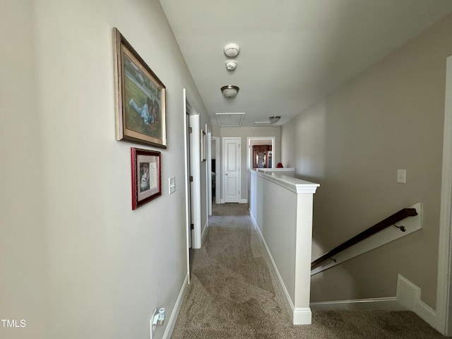 corridor with attic access, baseboards, carpet flooring, and an upstairs landing