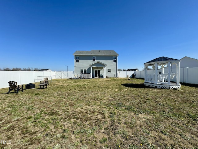 rear view of house with a yard, a fenced backyard, and a gazebo