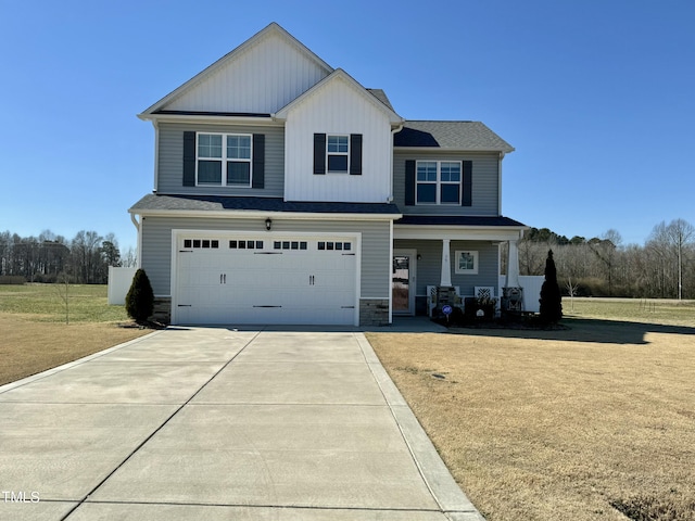 view of front of property featuring driveway, stone siding, an attached garage, a front lawn, and board and batten siding