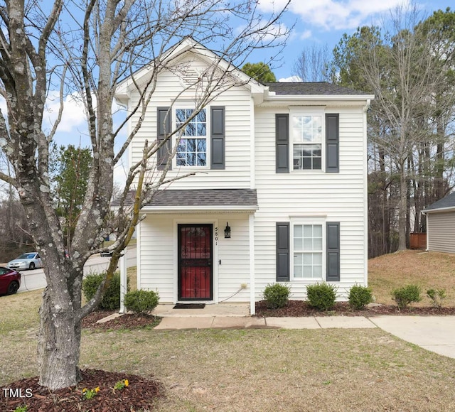 traditional-style home featuring a front lawn and roof with shingles