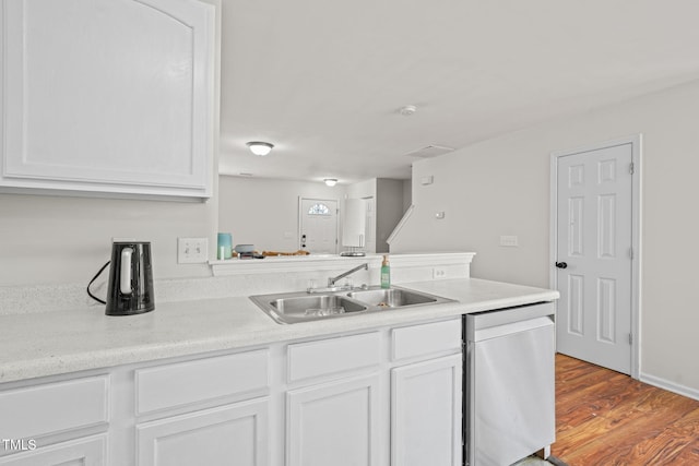 kitchen featuring a peninsula, a sink, white cabinetry, light countertops, and stainless steel dishwasher