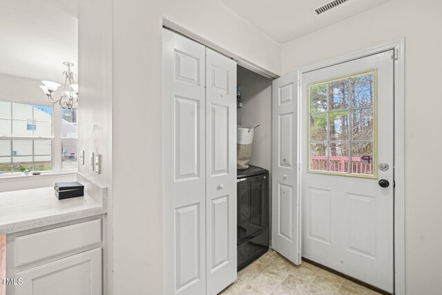 doorway featuring washer / dryer, visible vents, and a notable chandelier