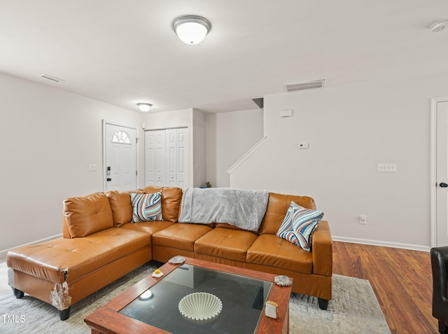 living area with baseboards, visible vents, and wood finished floors