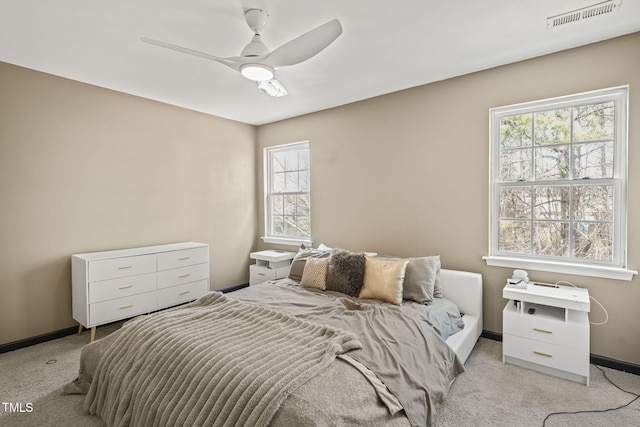 bedroom featuring baseboards, visible vents, a ceiling fan, and light colored carpet