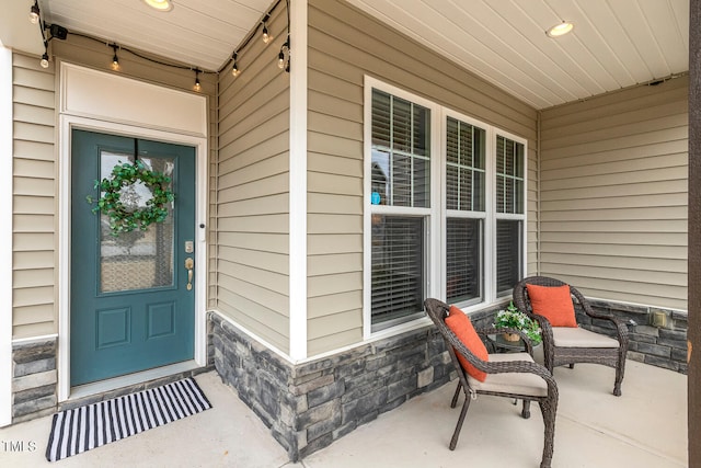 property entrance with stone siding and a porch