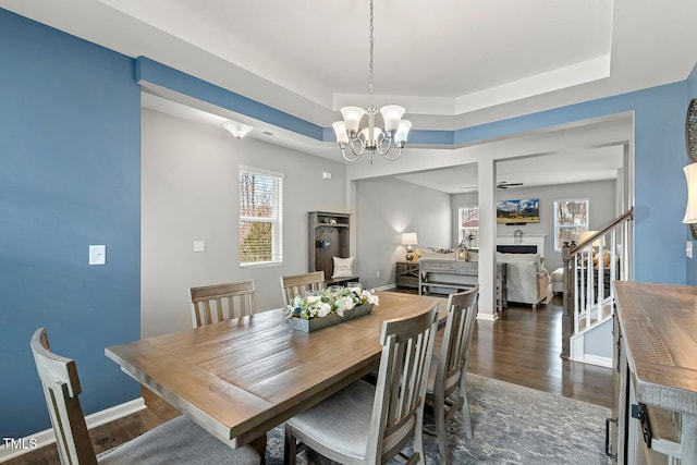 dining space with baseboards, stairway, an inviting chandelier, a raised ceiling, and dark wood-style flooring