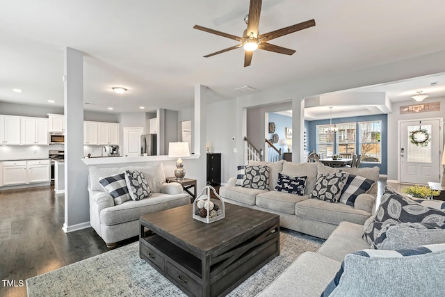 living area featuring baseboards, stairs, recessed lighting, ceiling fan with notable chandelier, and dark wood-style flooring