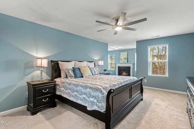 bedroom featuring baseboards, visible vents, a lit fireplace, and light carpet