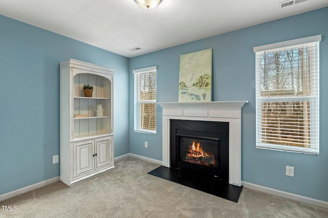 living area featuring visible vents, a fireplace with flush hearth, baseboards, and carpet