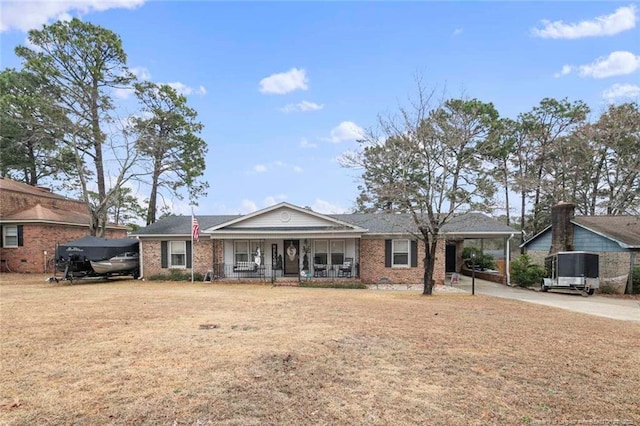 ranch-style house featuring brick siding, covered porch, a front yard, an attached carport, and driveway