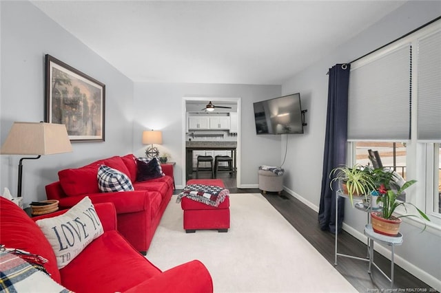 living room with ceiling fan, baseboards, and wood finished floors