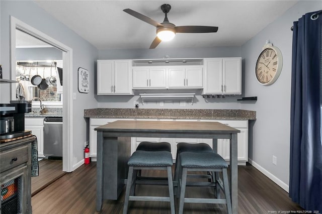 kitchen with dark wood-style floors, a breakfast bar area, white cabinets, and stainless steel dishwasher