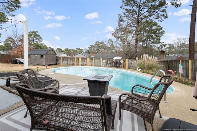 view of swimming pool featuring a fenced in pool, a patio area, a fenced backyard, and a storage unit