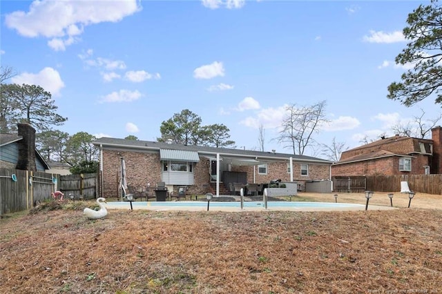 rear view of house featuring a patio area, a fenced backyard, a fenced in pool, and brick siding