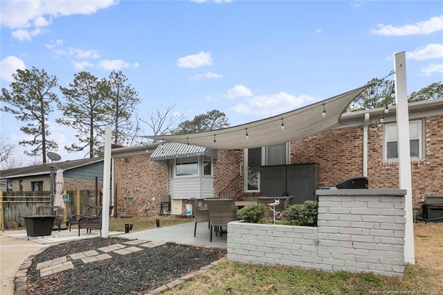 back of house with brick siding, a patio area, and fence