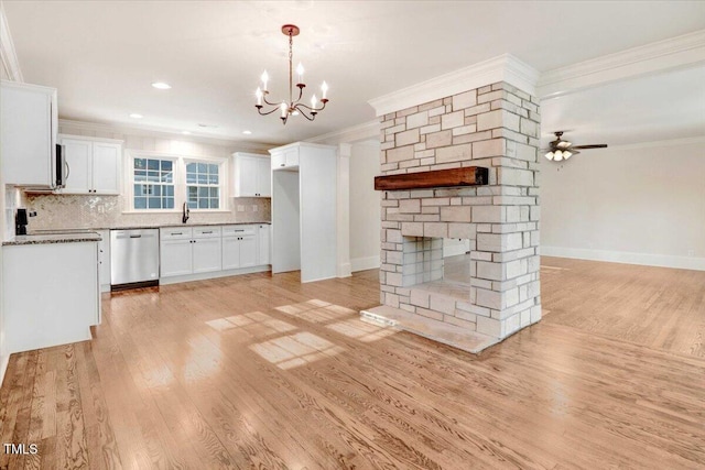 unfurnished living room featuring ornamental molding, a stone fireplace, light wood-type flooring, baseboards, and ceiling fan with notable chandelier