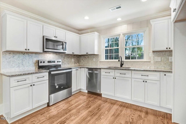 kitchen with appliances with stainless steel finishes, white cabinets, visible vents, and a sink